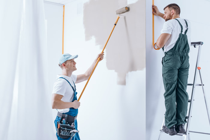 Professional painters in Oshawa painting interior walls with roller and ladder