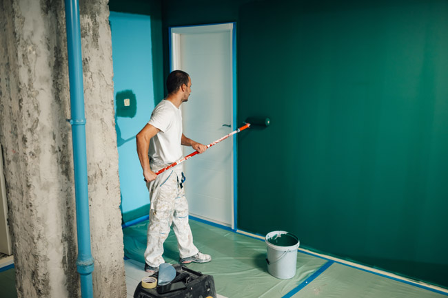 Painter applying teal wall color in apartment managed by HOA property management