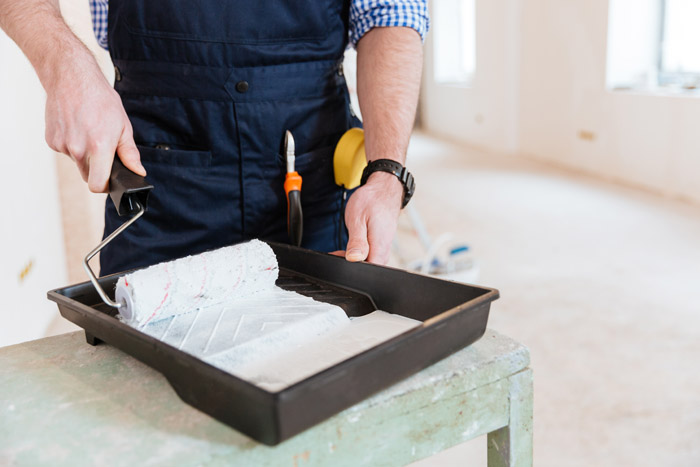 Painter preparing roller with white paint in London home
