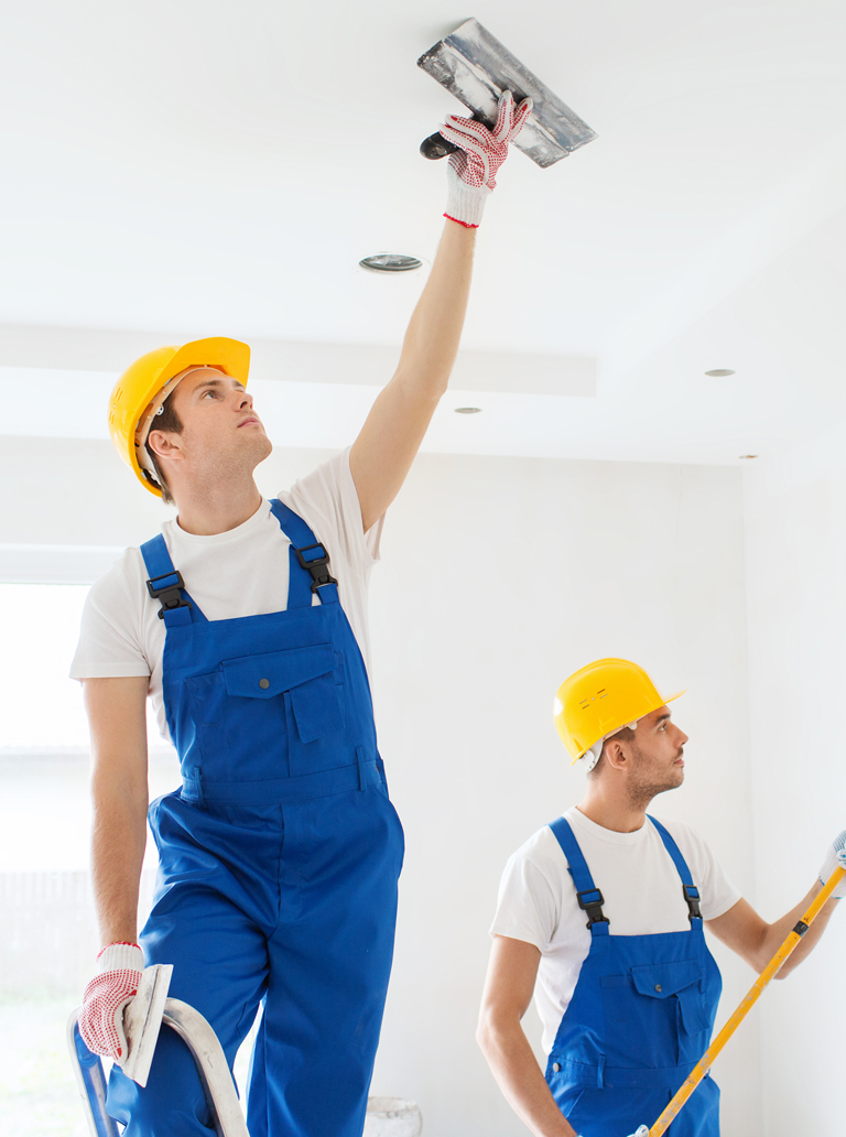 Professional painters repairing and painting ceiling in residential property