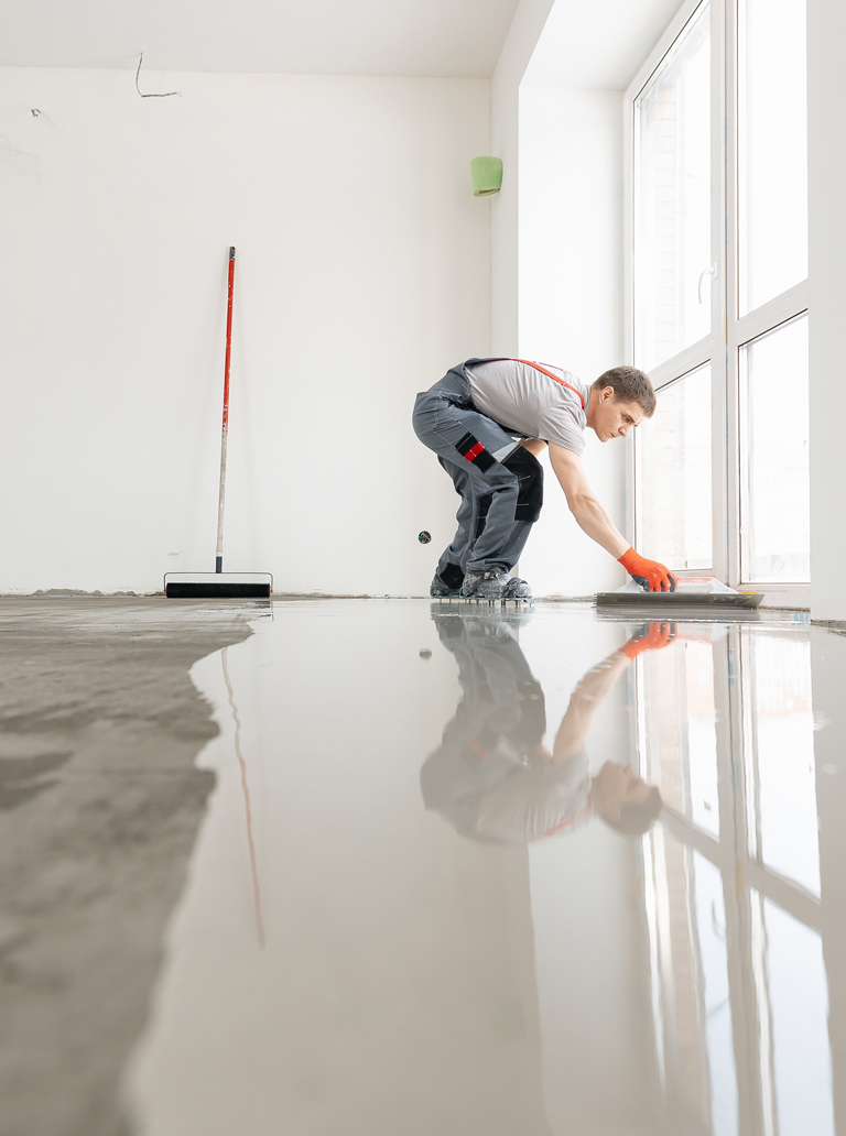 Worker leveling epoxy floor coating in residential interior