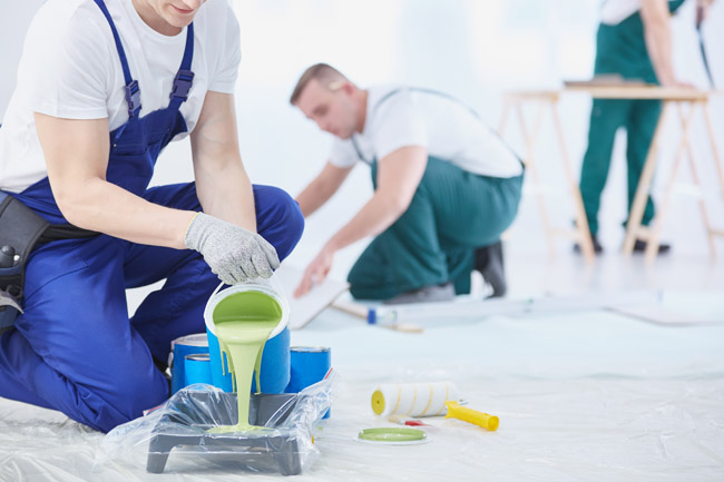 Professionals applying green epoxy floor coating during commercial renovation