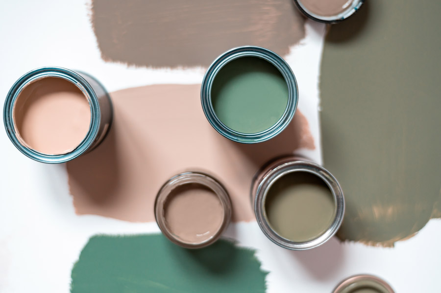 Open paint cans with earthy and green tones for wall color selection during professional color consultation