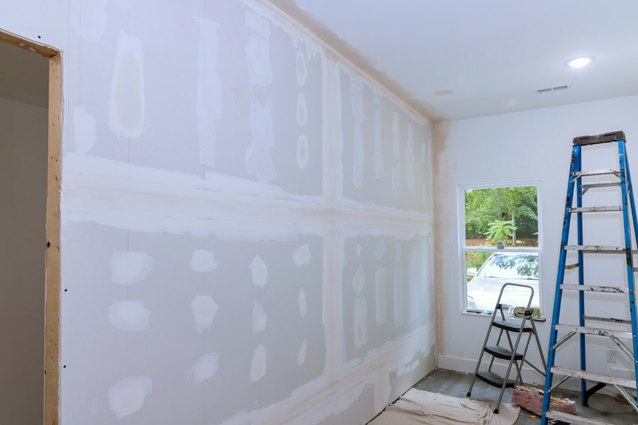 Drywall repair and preparation before interior painting with ladder and tools