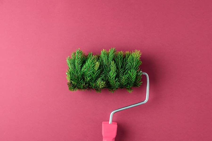 Eco-friendly painting concept with green paint roller covered in pine branches