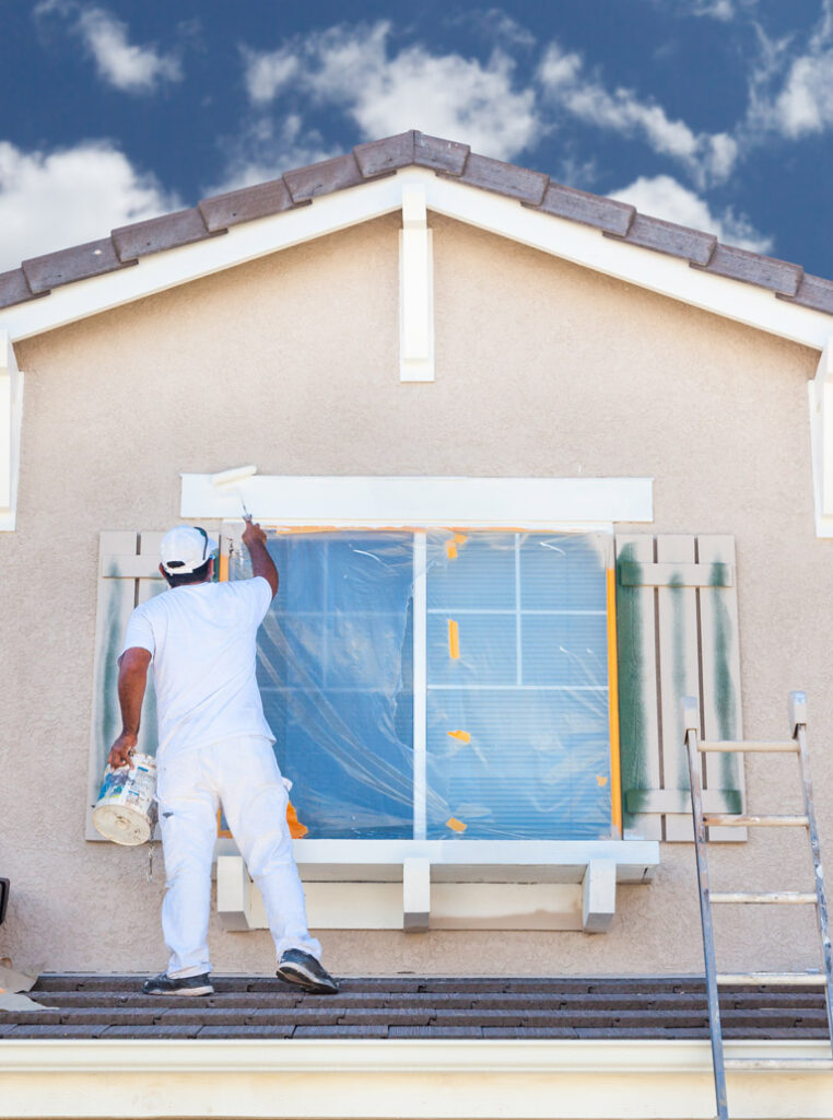 Professional painter applying exterior paint on a house facade in Kitchener