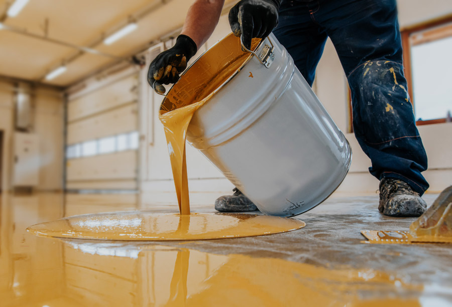 Epoxy floor coating Toronto — technician pouring yellow resin by Walls Master