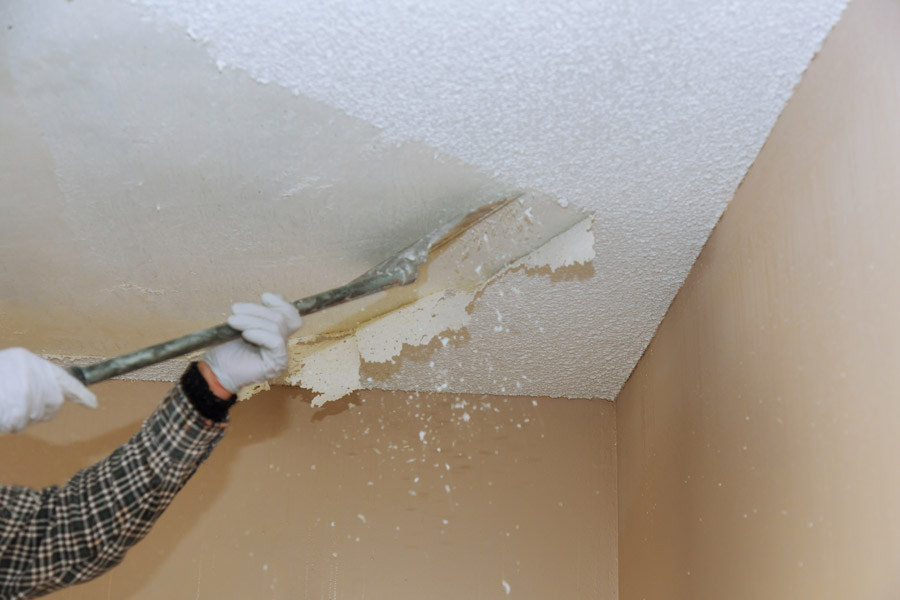 Popcorn ceiling removal process — worker scraping stucco ceiling in Toronto home
