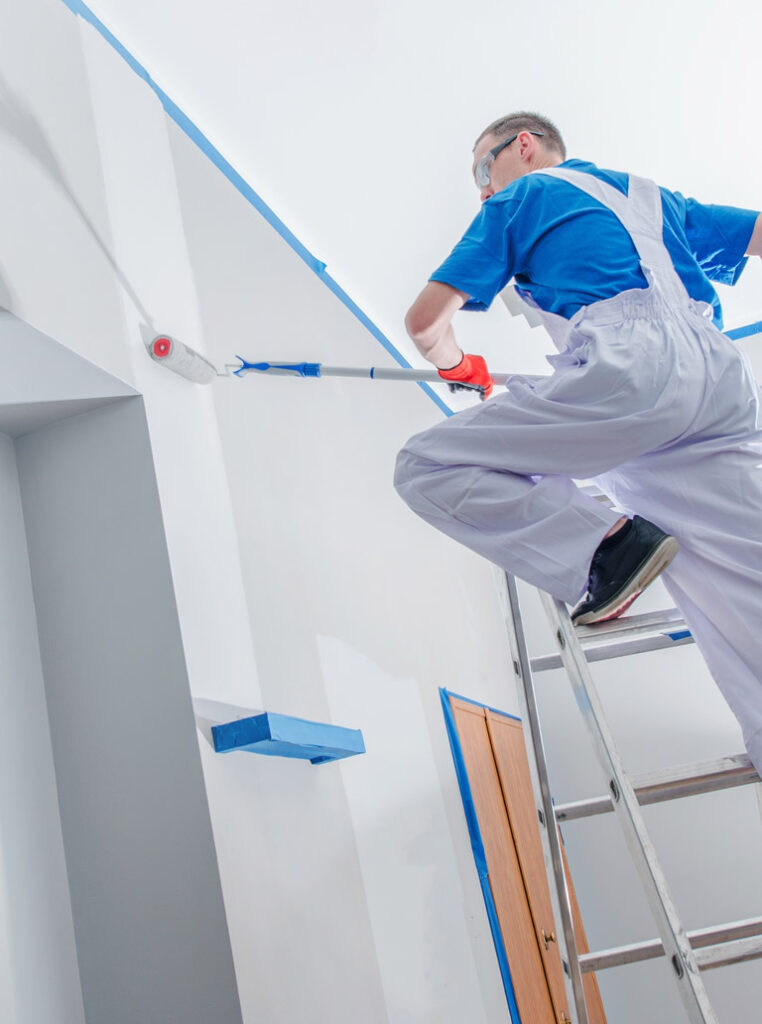 Professional painter in Kitchener painting high interior walls using roller and ladder